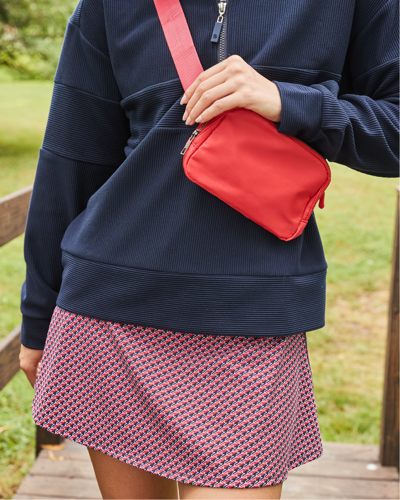 Model is wearing the Ribbed Varsity Quarter Zip in Nave with the Flounce Skort in Navy/ Cherry Stars