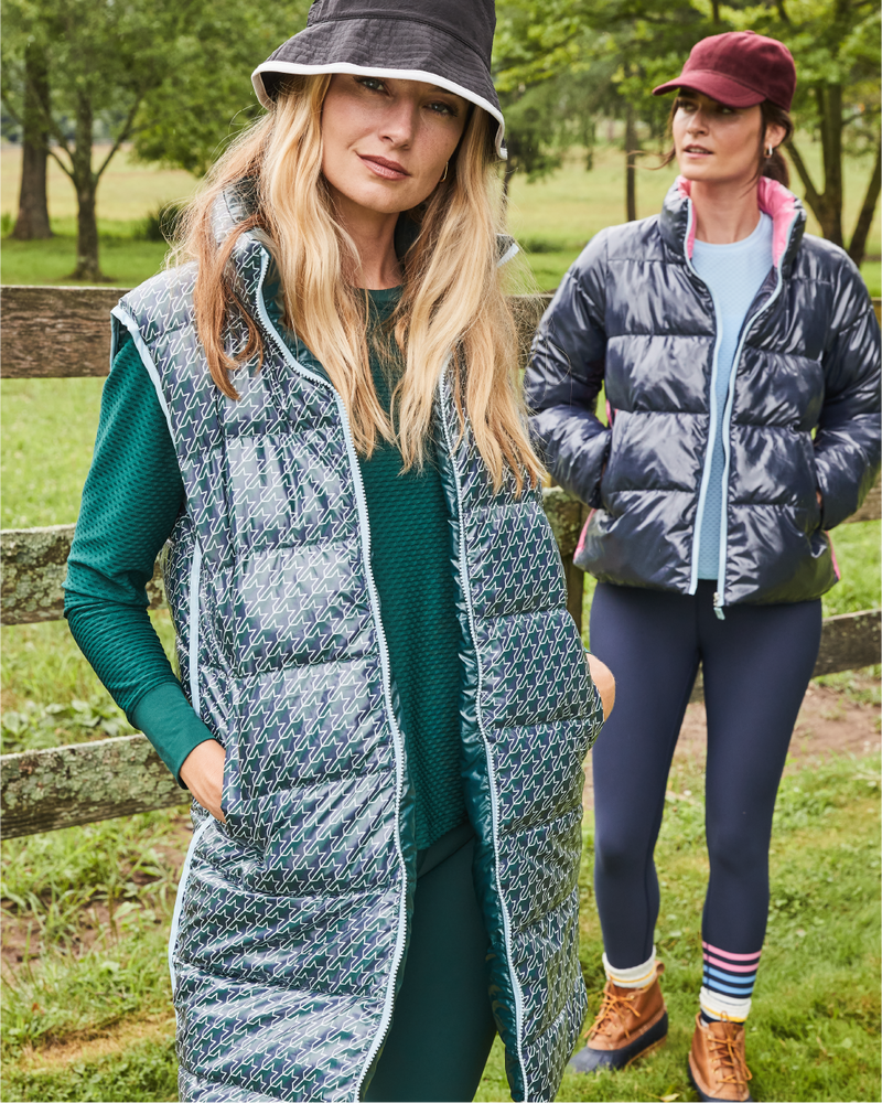 Model left is wearing the Everywhere Reversible Puffer Vest in Stars Ivy with the Palmetto Long Sleeve in Ivy and the Everyday Leggings in Ivy. Model right is wearing the Everyday Puffer Jacket in Navy with the Palmetto Long Sleeve in Baby Blue and the Everyday Legging in Navy Peony/ Matisse Stripe.