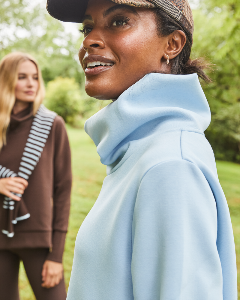 Model right is wearing the Everyday Pullover in Baby Blue. Model left is wearing the Everyday Pullover in Chocolate and the Everyday Leggings in Chocolate with the Carlyle Crewneck in Chocolate/ Baby Blue Stripes around her shoulders. 