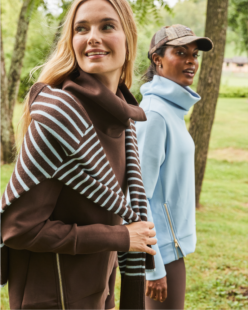 Model left is wearing the Everyday Pullover in Chocolate with the Carlyle Crewneck in Chocolate around her shoulders. Model right is wearing the Everyday Pullover in Baby Blue with the Everyday Legging in Chocolate. 