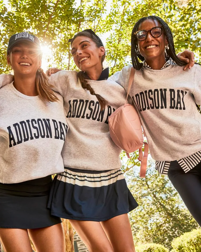 Model 1 is wearing College Crewneck in Light Grey with Everyday Skort in Navy. Model 2 is wearing College Crewneck in Light Grey layered over Palm Beach Dress in Navy / White Stripe. Model 3 is wearing College Crewneck in Light Grey layered over Assembly Button Down in Navy and Everyday Legging in Navy.
