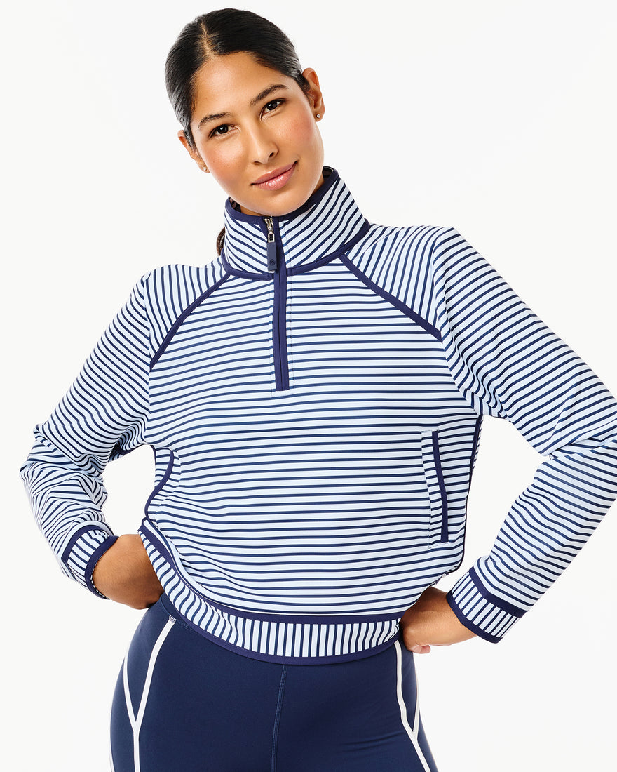 Model is wearing the bainbridge quarter zip in super white cerulean stripe with the flounce skort in cerulean.
