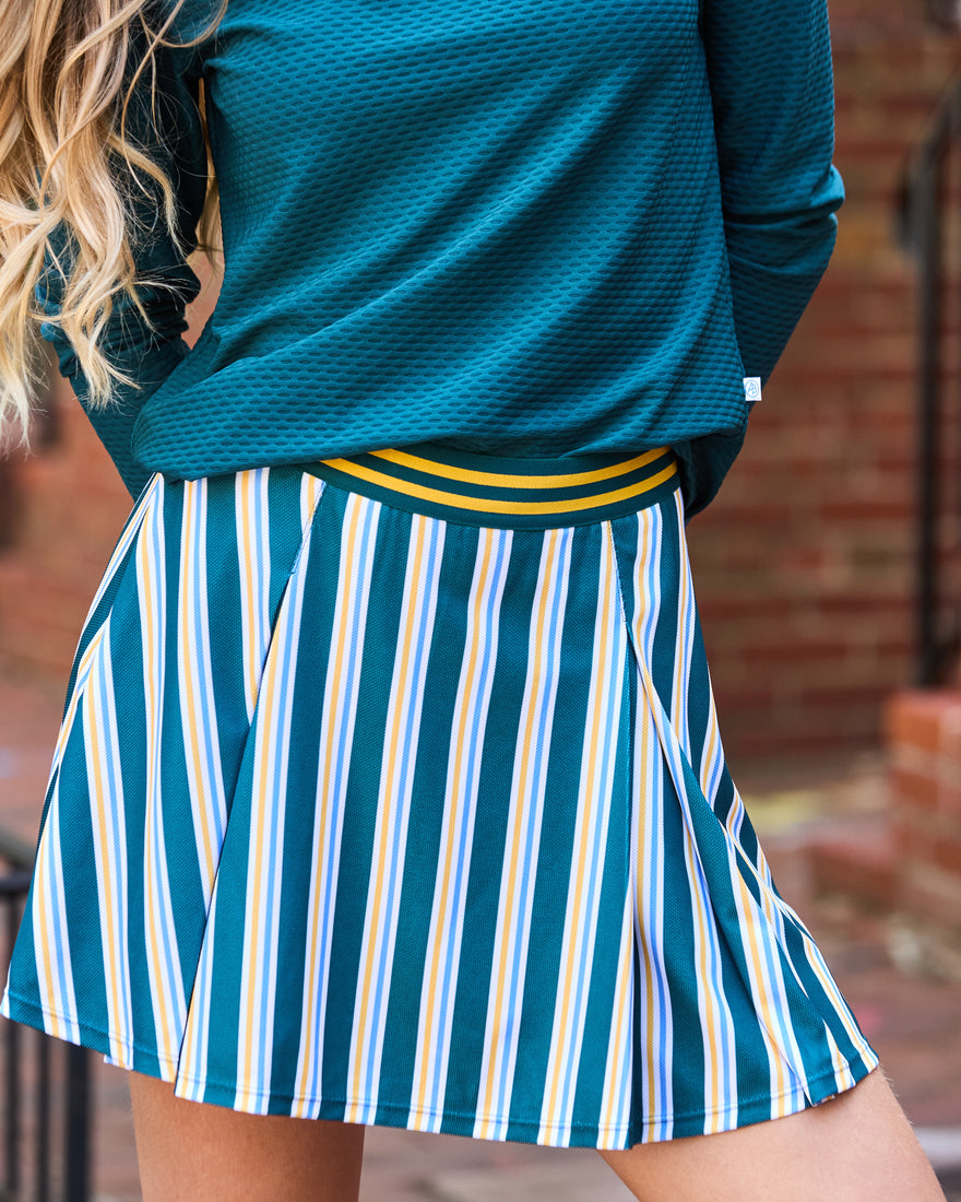 Model is wearing the walnut long sleeve in super white paired with the breakpoint skort in bubblegum/ivy