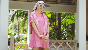 Model is wearing the Sailor Dress in Peony with the Carlyle Crewneck in Petal/Peony Stripe around her shoulders