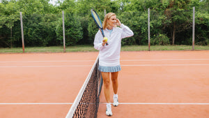 Marghi is wearing the Varsity Quarter Zip in Super White over the Everyday Tank in Baby Blue with the Court Skort in Super White/Baby Blue/Ivy Stripe