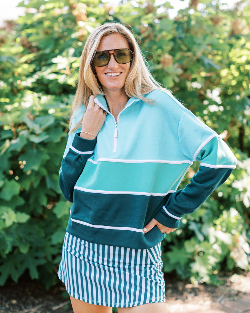 Model is wearing the JV Quarter zip in alo/ sage/ ivy paired with the everyday skort in ivy/ mint triple stripe. 